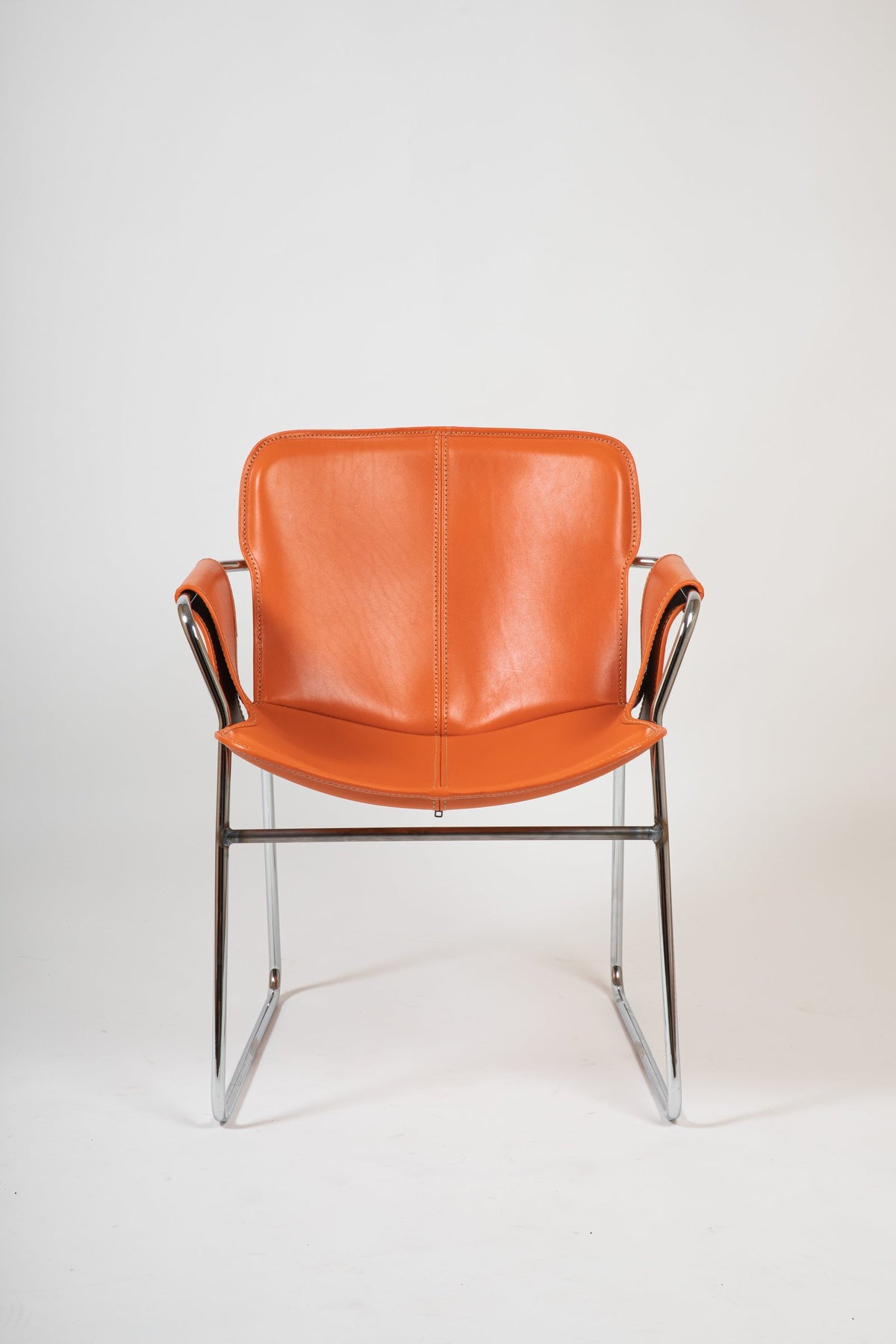 Orma armchair by André Ricard for Isist Atelier: orange leather cover over a polished stainless steel frame
