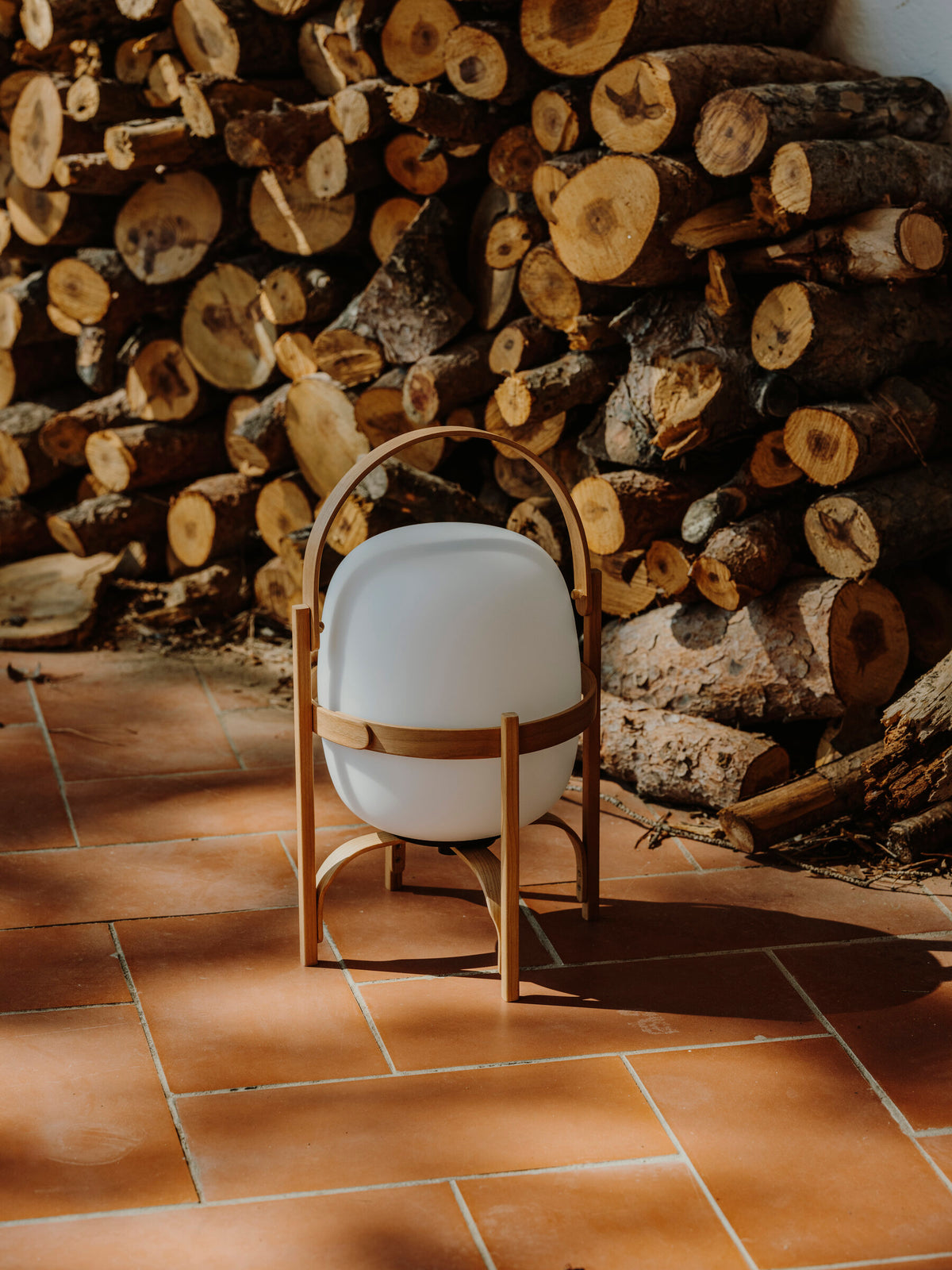 Cestita Batería portable lamp in front of stacked firewood at Casa Ugalde
