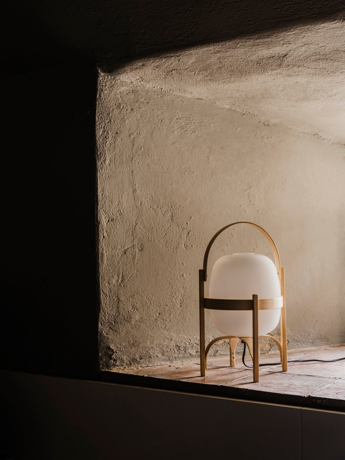 Cestita lamp switched off in a rough plaster wall niche