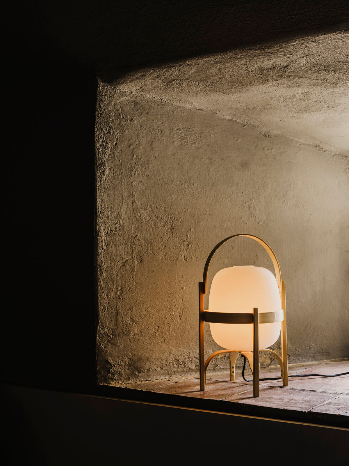 Cestita lamp switched on in a rough plaster wall niche