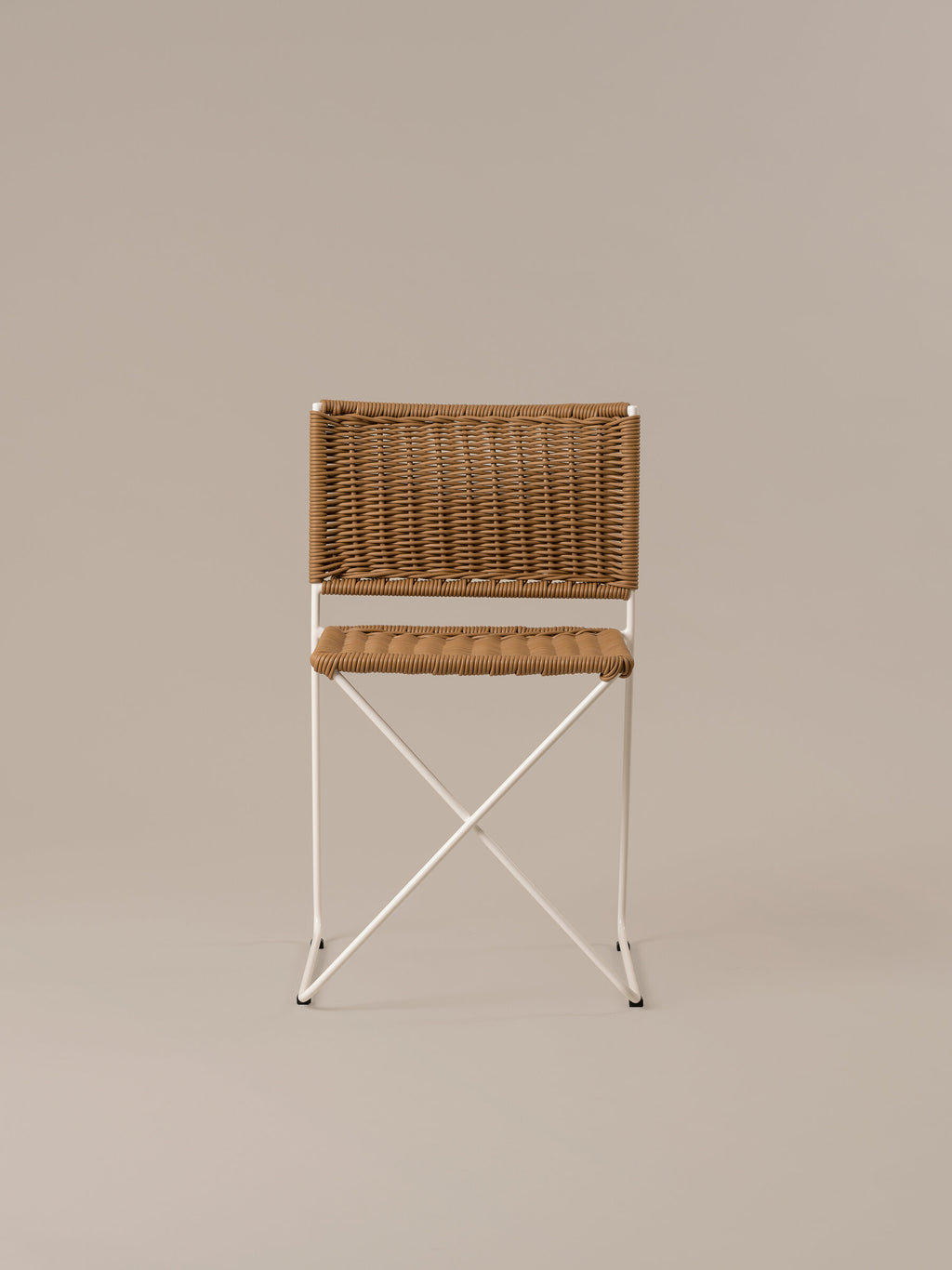 Front view of the Ramón chair in natural rattan, showing the crossed bar beneath the seat