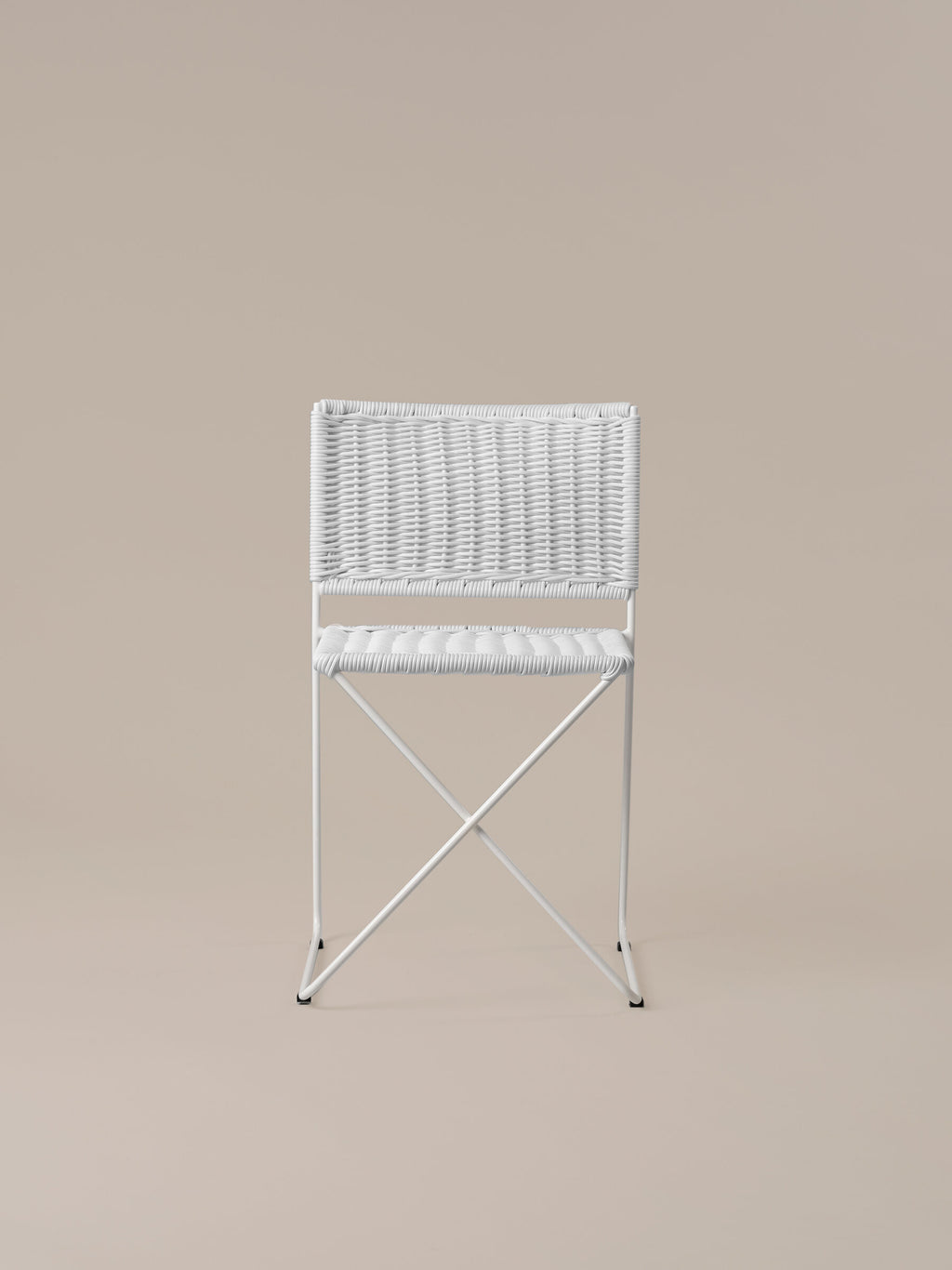 Front view of the Ramón chair in white rattan, showing the crossed bar beneath the seat
