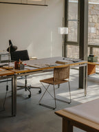Ramón chair in natural rattan at a desk in an office with large windows