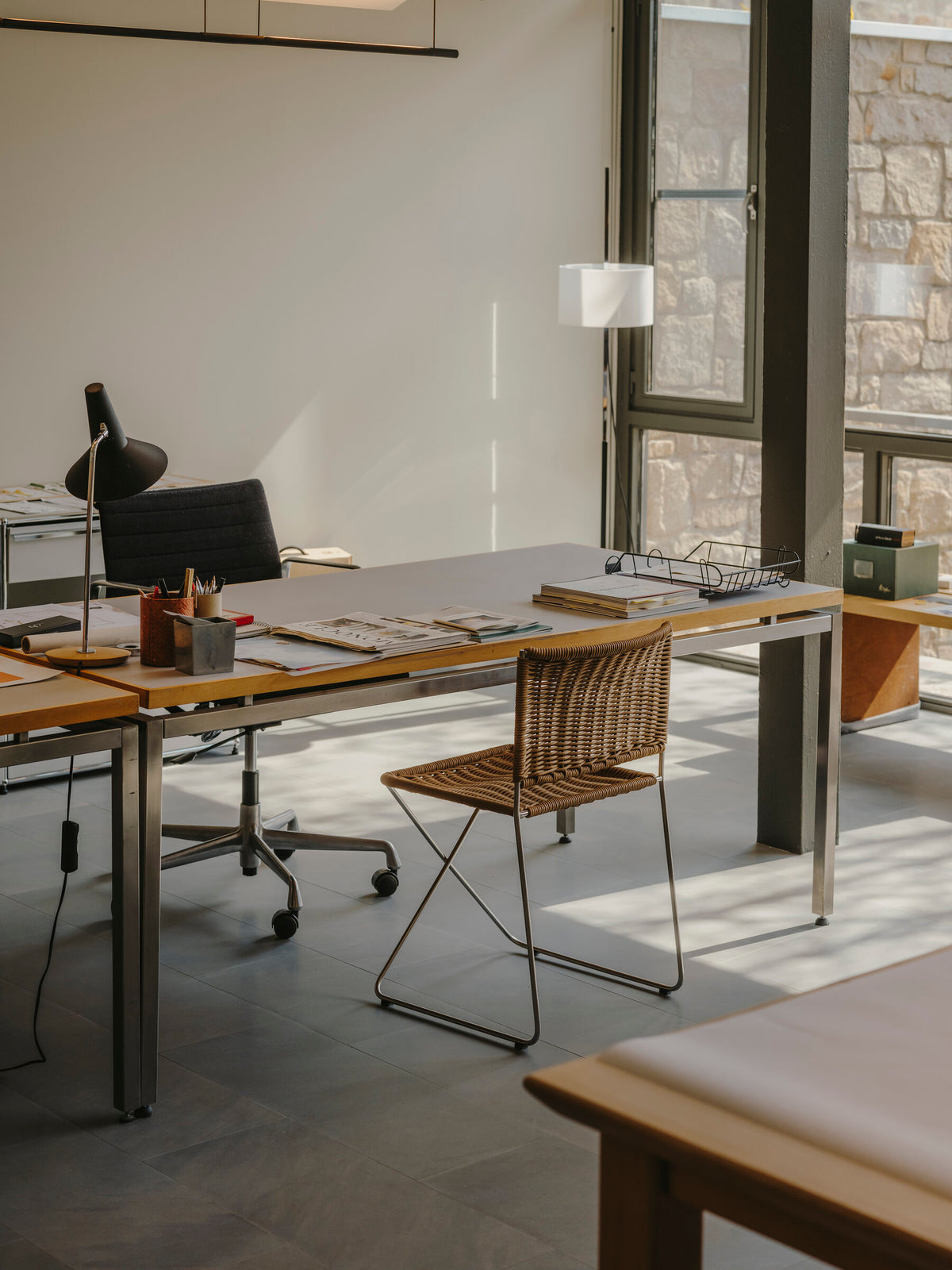 Ramón chair in natural rattan at a desk in an office with large windows