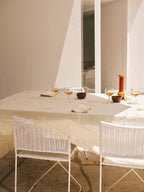 Ramón chairs in white rattan around a dining table in sunlight