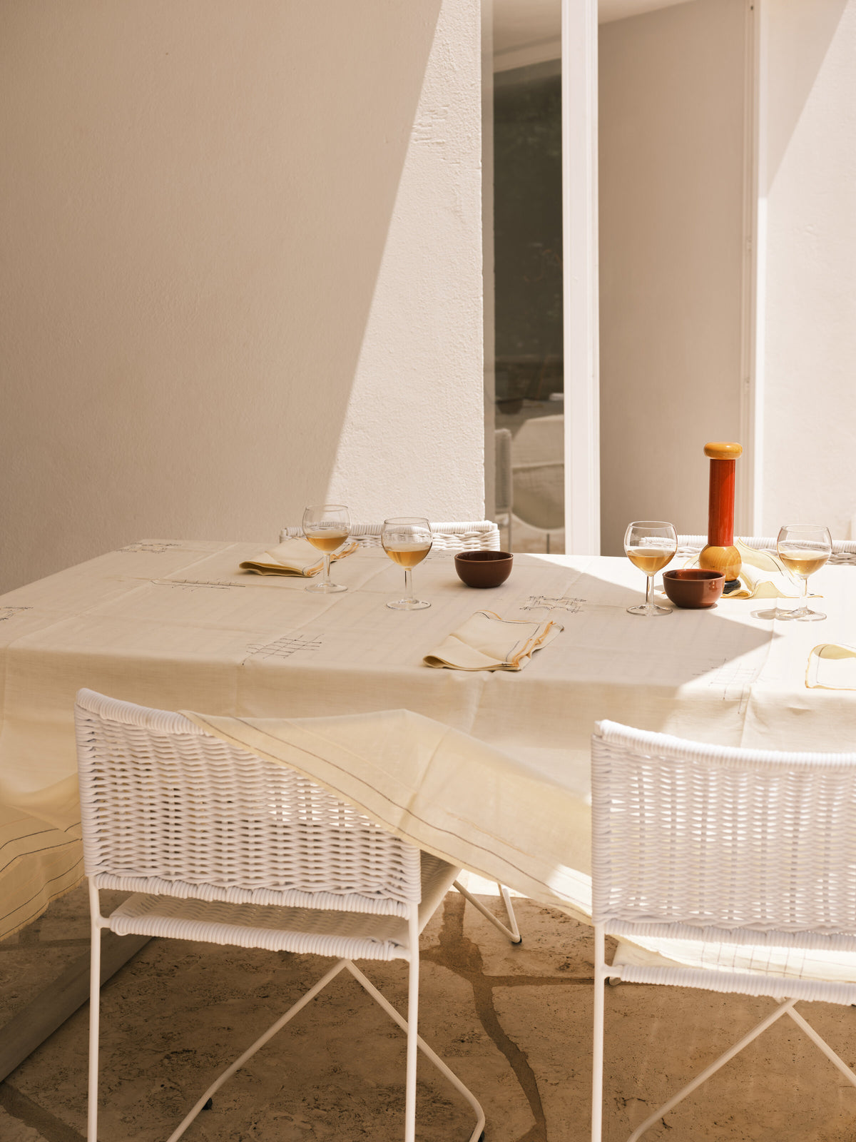 Ramón chairs in white rattan around a dining table in sunlight