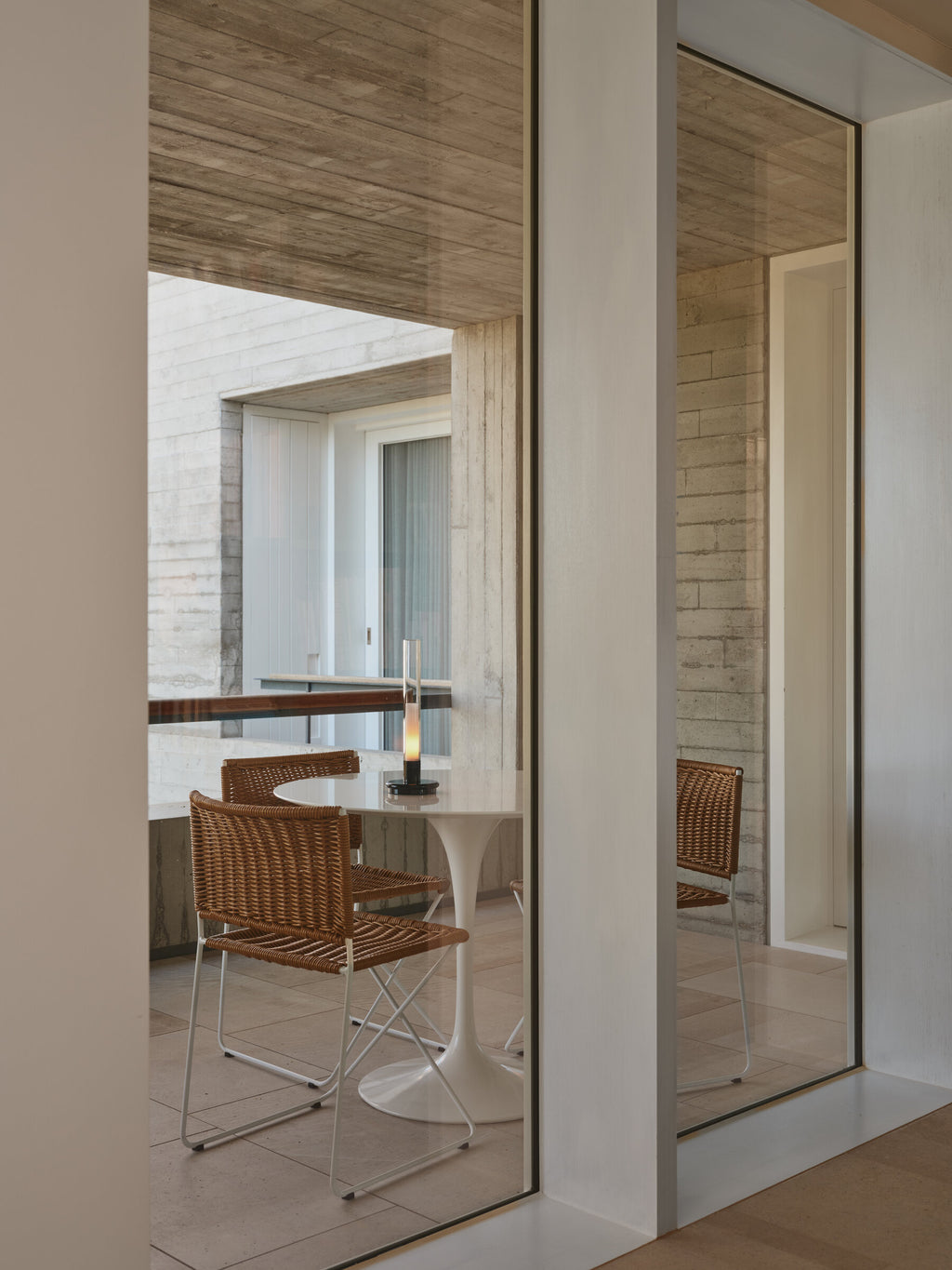 Ramón chair in natural rattan at a round table, seen through a doorway
