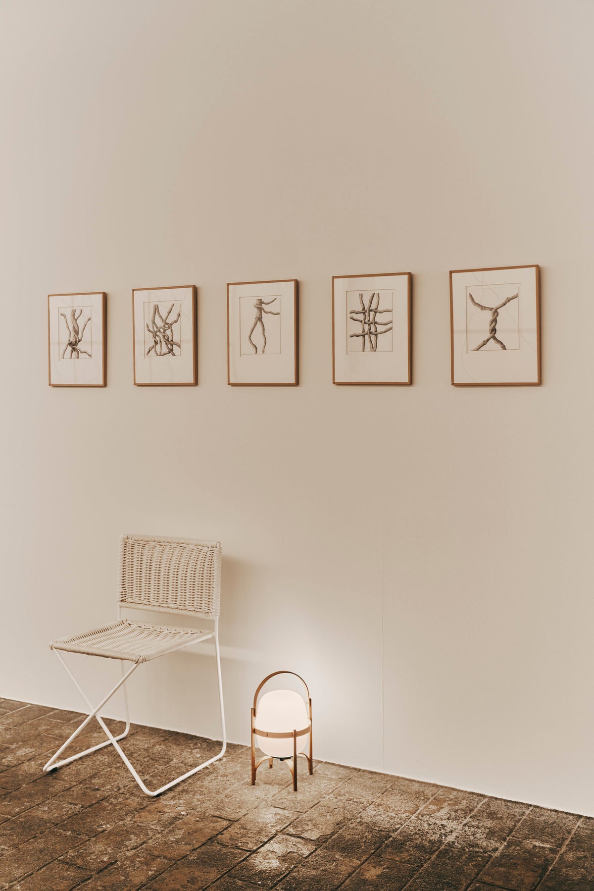 Ramón chair in white rattan in a gallery, below framed drawings