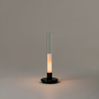 Sylvestrina portable lamp by Santa & Cole with a black base and clear glass tube, switched on