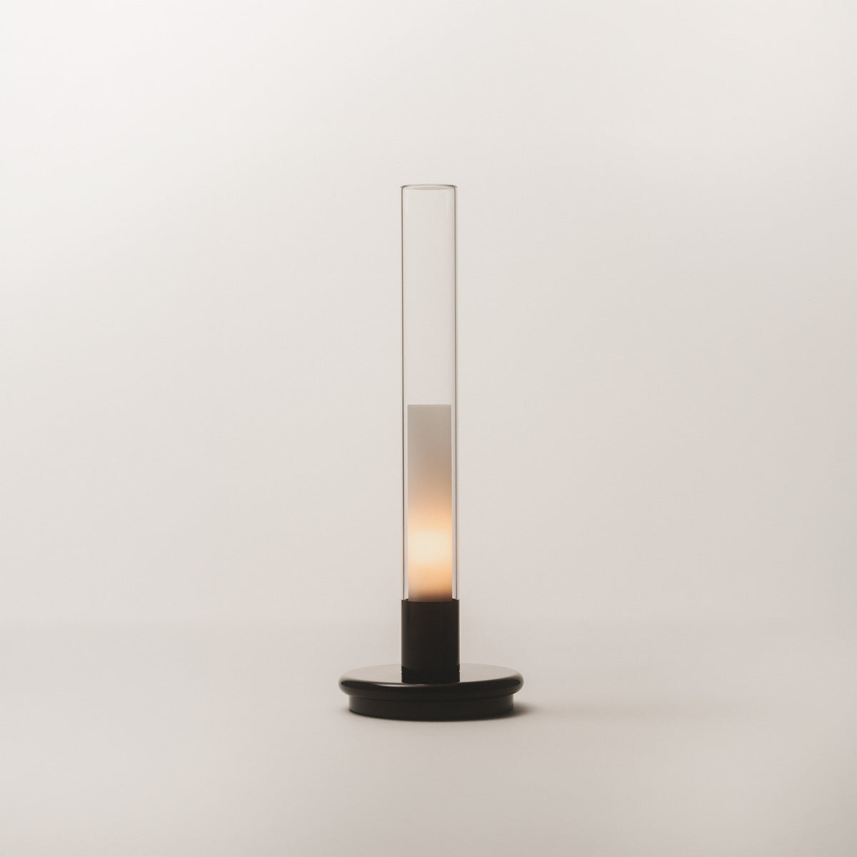Black Sylvestrina portable lamp on a white surface, switched on