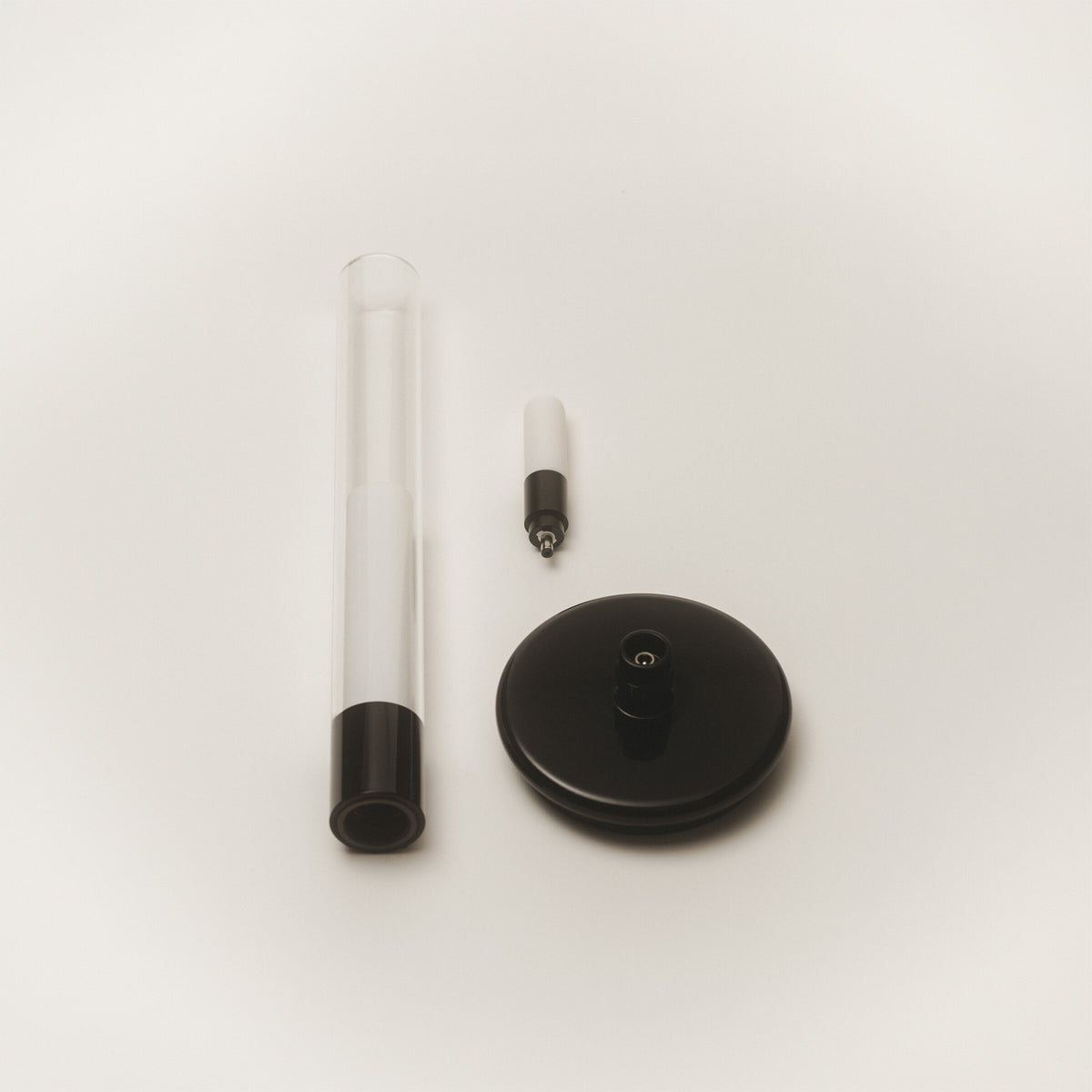 Sylvestrina portable lamp taken apart: glass tube, light source, and base