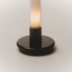 Detail of the black base of the Sylvestrina portable lamp, switched on