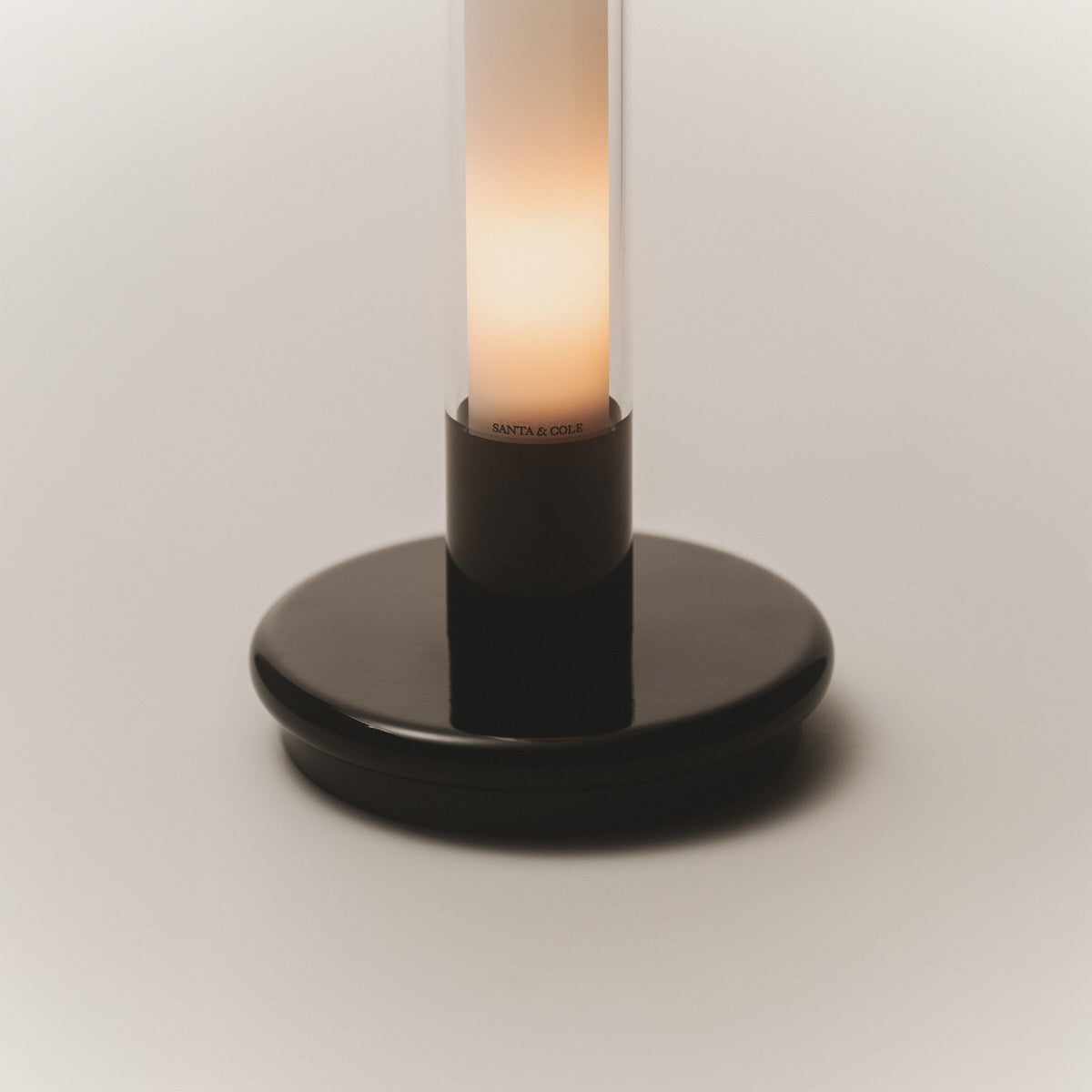 Detail of the black base of the Sylvestrina portable lamp, switched on