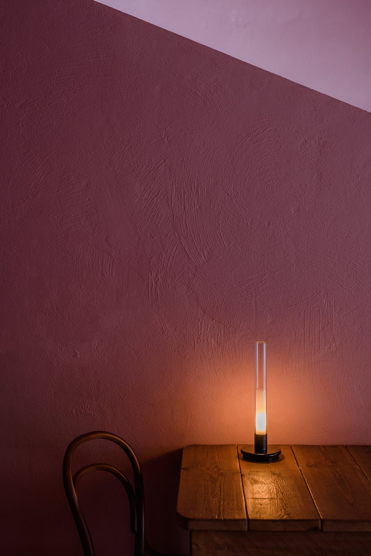 Sylvestrina portable lamp on a small wooden table against a red wall