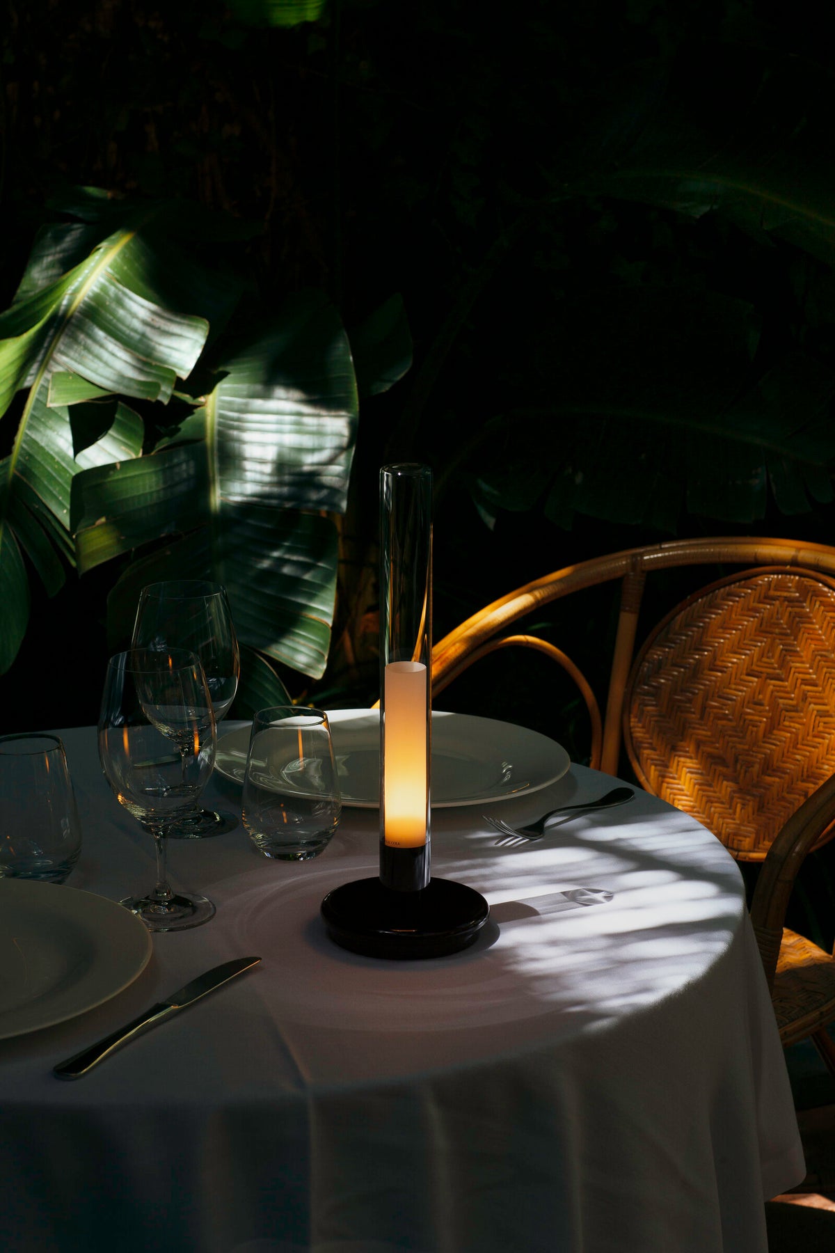 Sylvestrina portable lamp on a table set for dinner outdoors at night