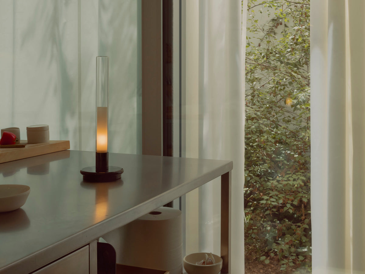 Sylvestrina portable lamp on a steel counter beside a garden window