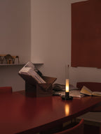Sylvestrina portable lamp on a red table beside a book stand