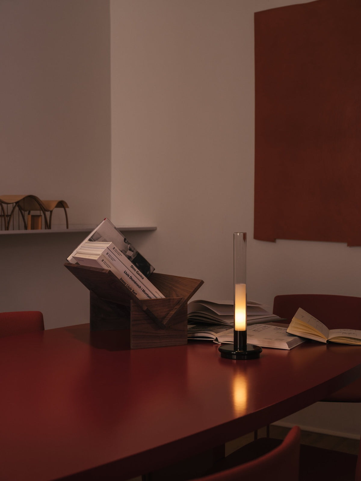Sylvestrina portable lamp on a red table beside a book stand