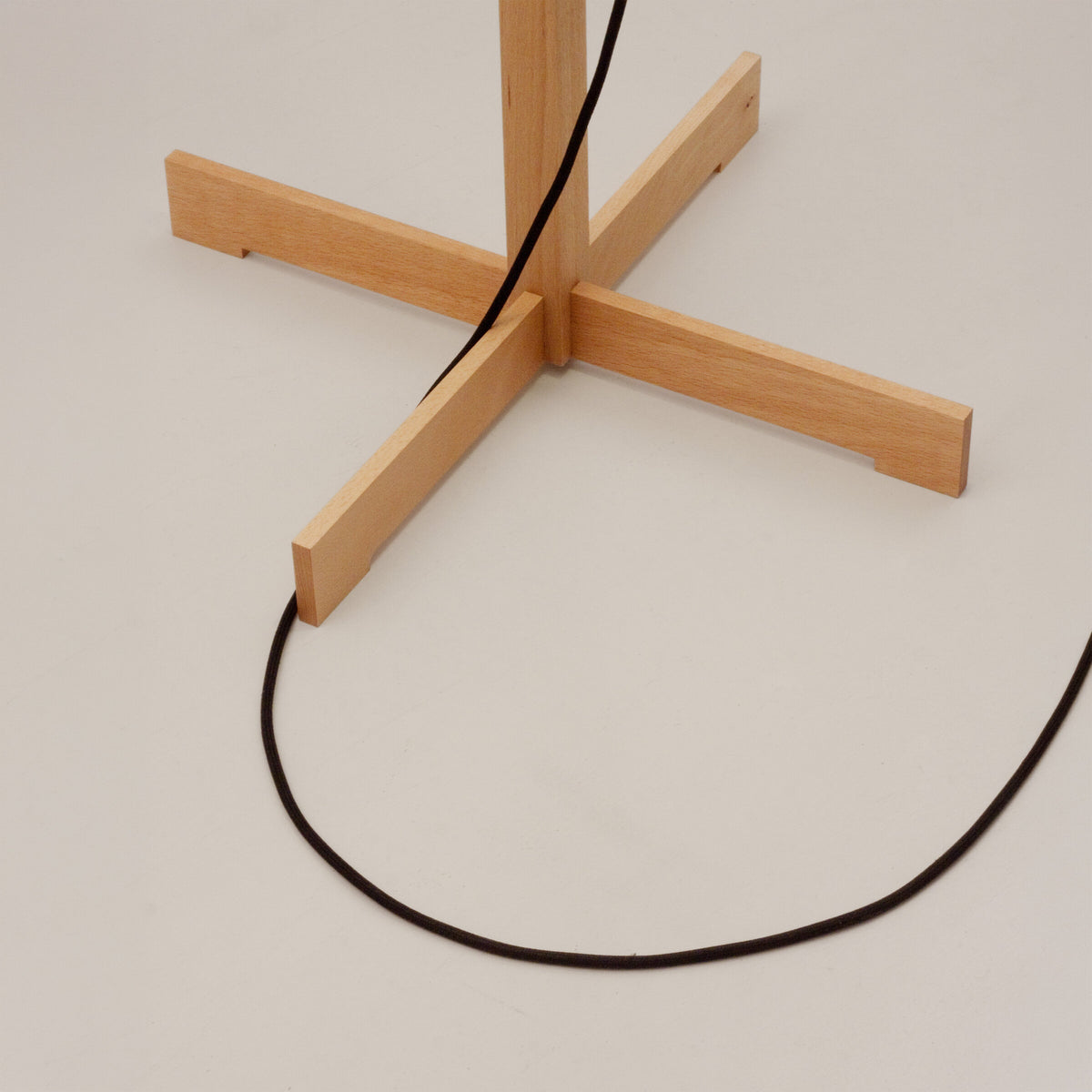 Detail of the cross-shaped wooden base of the TMM floor lamp