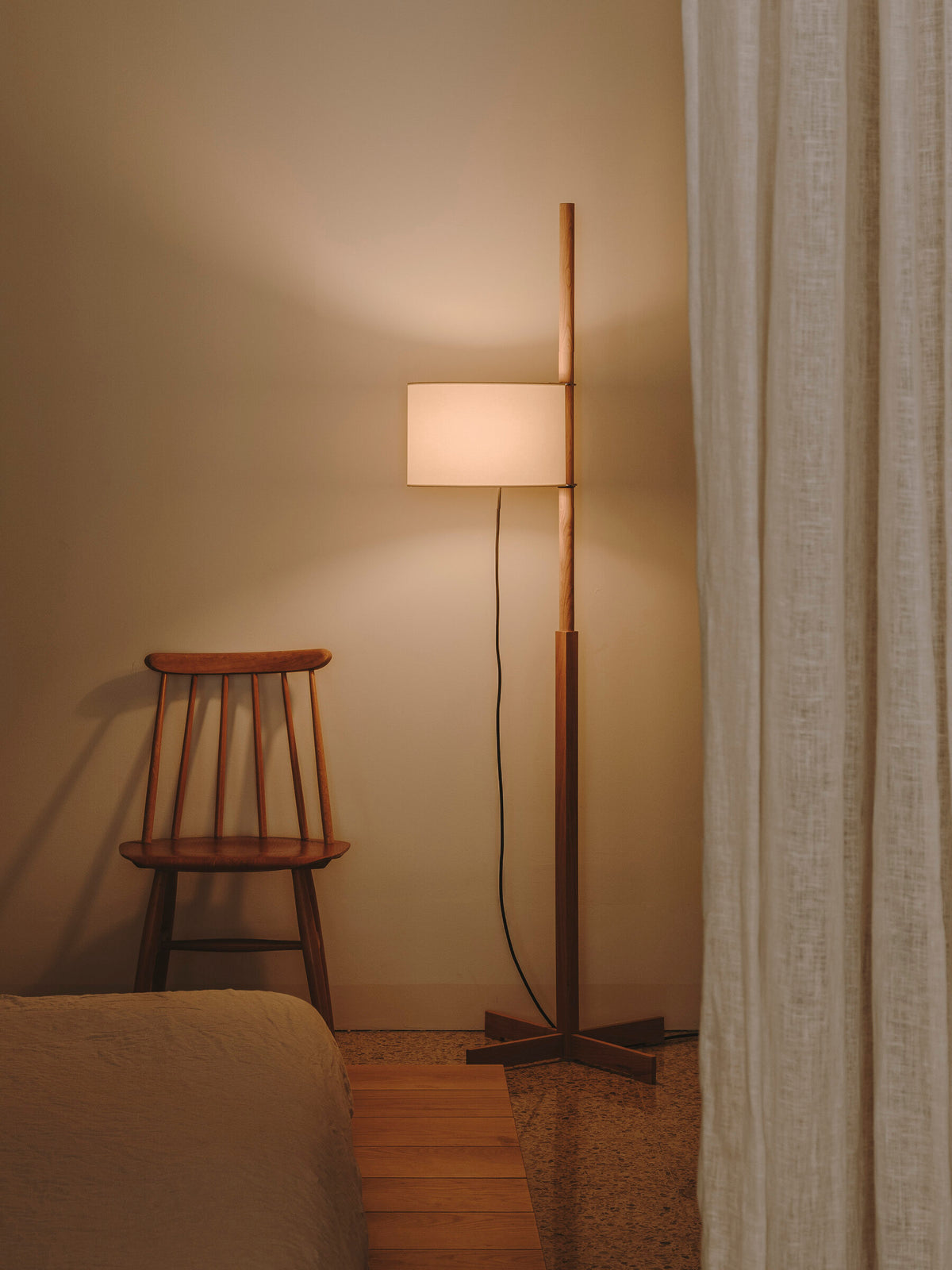 Lámpara de pie TMM con pantalla beige junto a una silla de madera